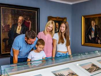 Eine Familie betrachtet Exponate im Liechtensteinischen Landesmuseum in Vaduz, umgeben von historischen Gemälden und Porträts.